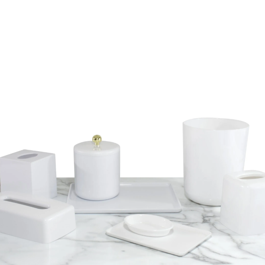 White ceramic bathroom accessories including a candle, soap dish, and cups on a marble surface.