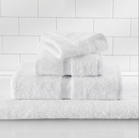 Stack of white towels on a white tiled wall background