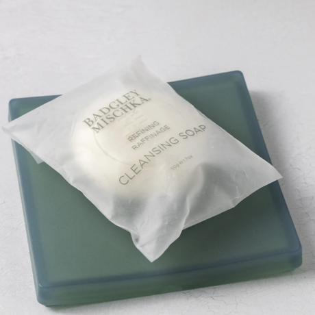Bar of soap with a white packet on a light gray background