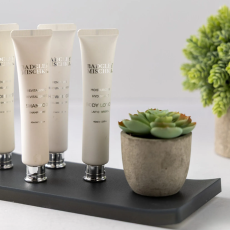 large amenity tray in dark gray with lotions and plant on top.