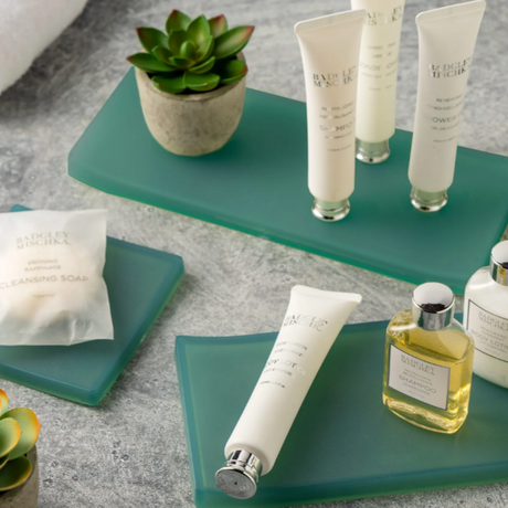 variety of green amenity trays with lotions and soaps on top.