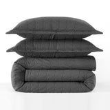 Stack of gray quilted pillows and comforter on a white background
