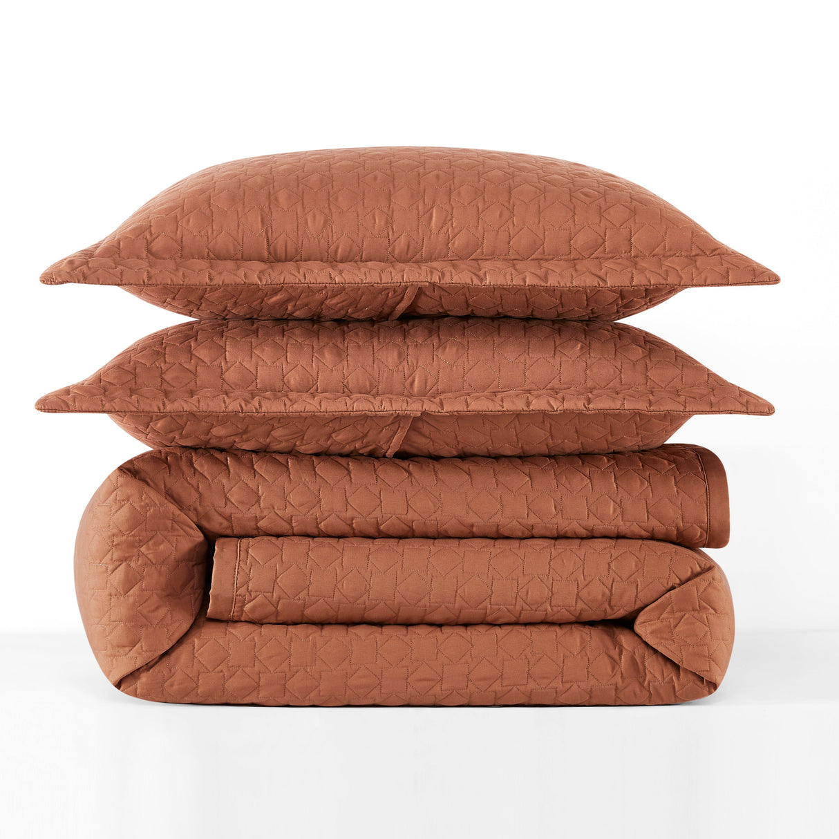Brown quilt and pillows stacked on a white background