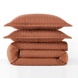 Brown quilt and pillows stacked on a white background