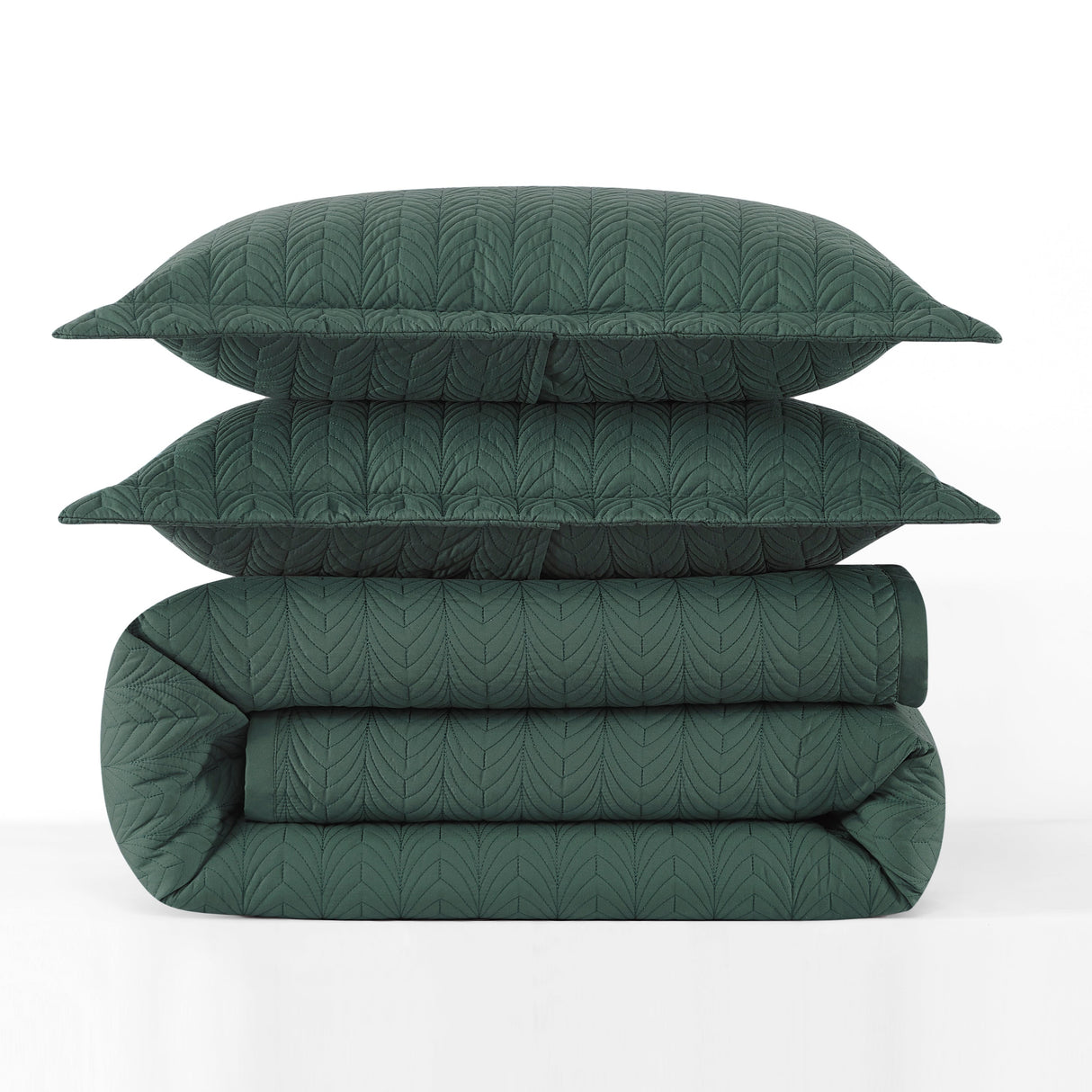 Green quilt and pillows stacked on a white background