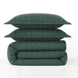 Green quilt and pillows stacked on a white background