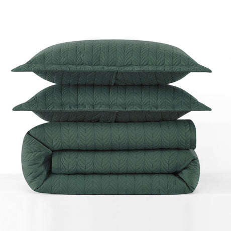 Green quilt and pillows stacked on a white background