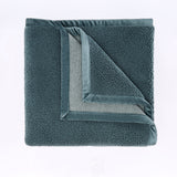 Folded gray fleece blanket on a light purple background