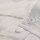 Close-up of a white textured fabric with buttons and a zipper.