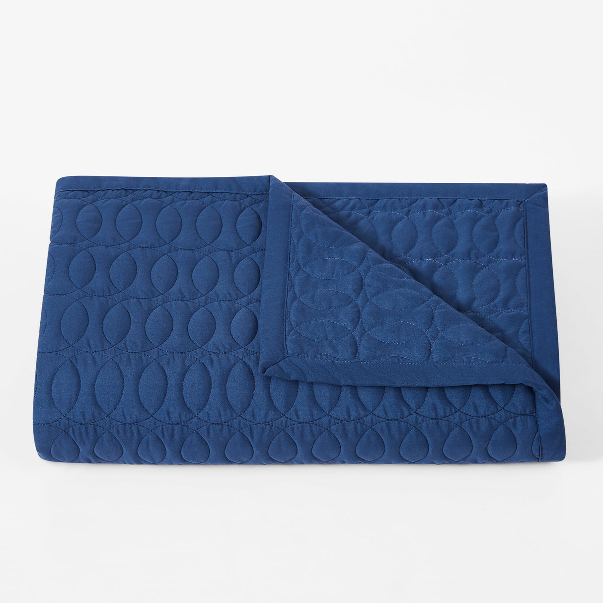 Folded blue quilt with a geometric pattern on a white background