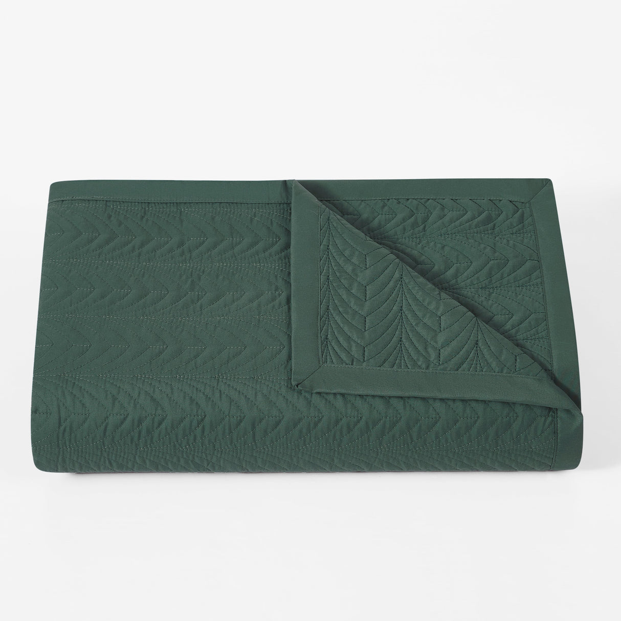 Green quilted blanket on a white background