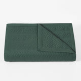 Green quilted blanket on a white background