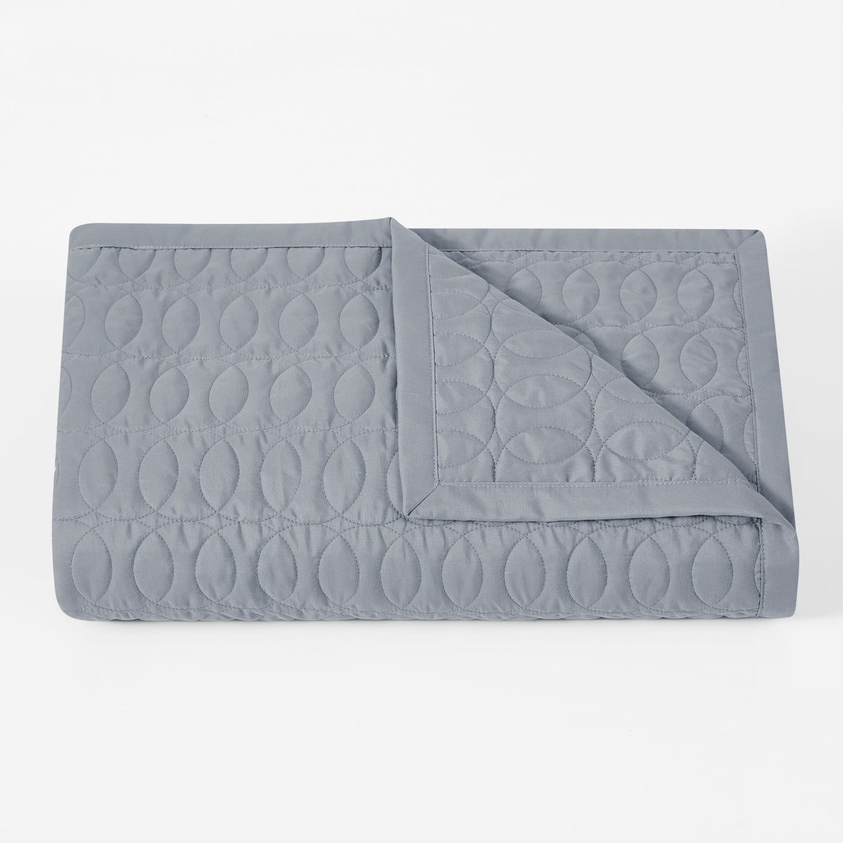 Folded gray quilt with a geometric pattern on a white background