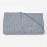 Folded gray quilt with a geometric pattern on a white background