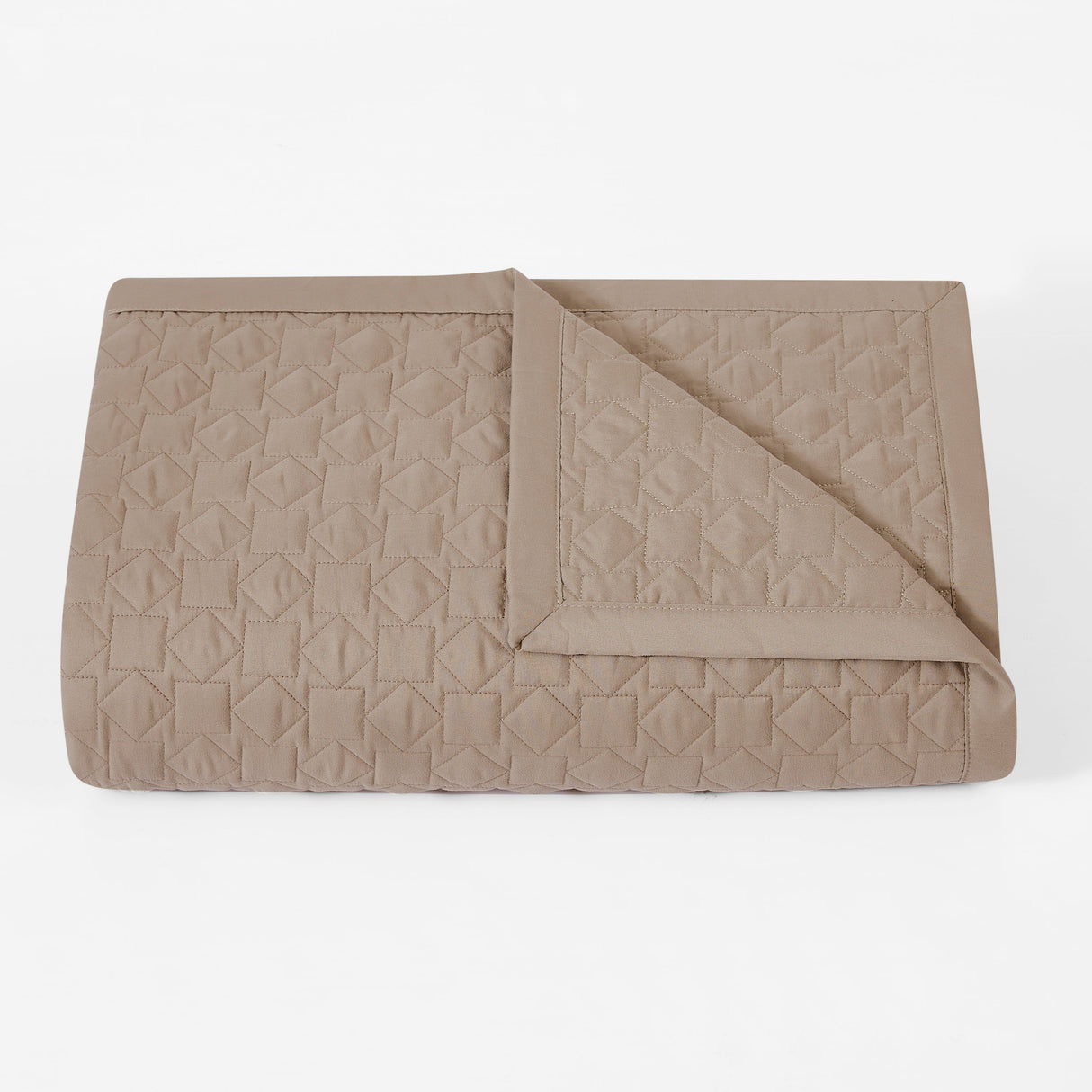 Folded beige quilt with geometric pattern on a white background