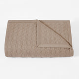 Folded beige quilt with geometric pattern on a white background