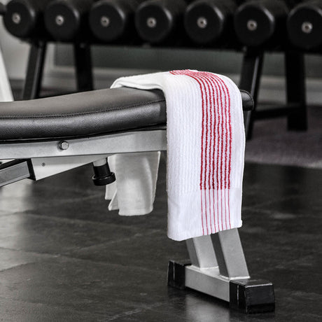 Gym bench with a towel draped over it in a gym setting