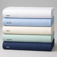 Stack of folded sheets in white, sky blue, bone, seafoam, and navy on a gray background.