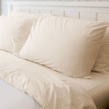 Bed sheet set in a beige/bone color showcased on fluffy pillows and duvet. High quality hotel linens. 