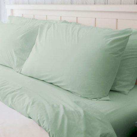 High quality hotel linens in a pastel green color. Features fluffy pillows and duvet. Wholesale supply. Product shot.