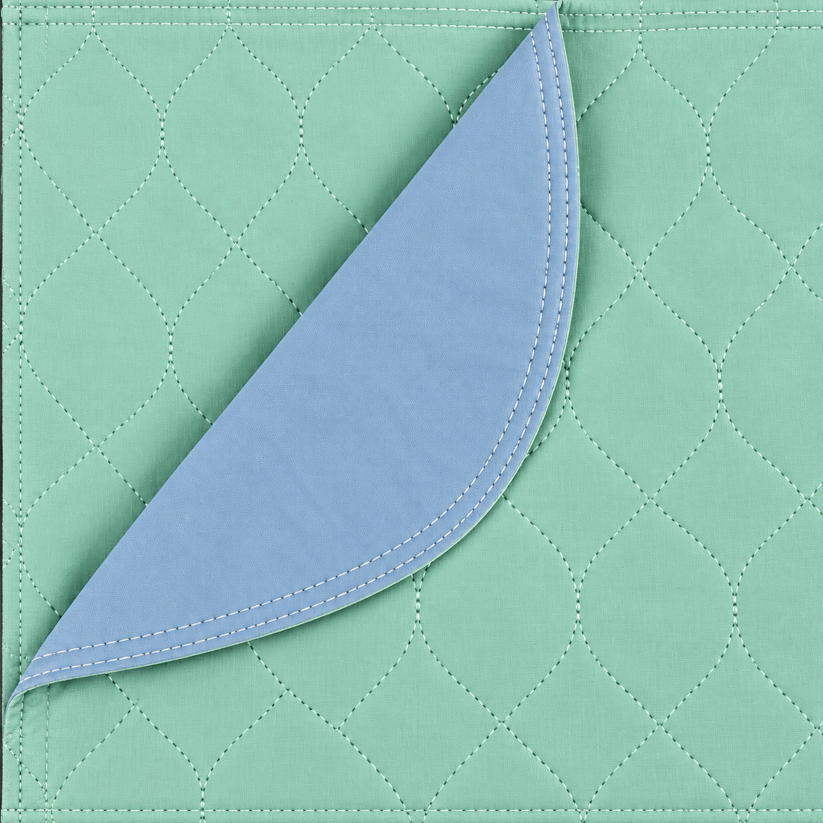 Pictured: The green Arid Touch Under Pad takes up the whole frame. It is partially folded over to show the blue vinyl lining that is on the bottom of the pad.