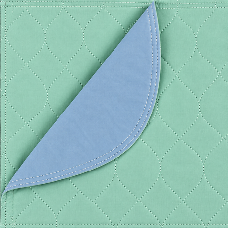 Pictured: The green Arid Touch Under Pad takes up the whole frame. It is partially folded over to show the blue vinyl lining that is on the bottom of the pad.