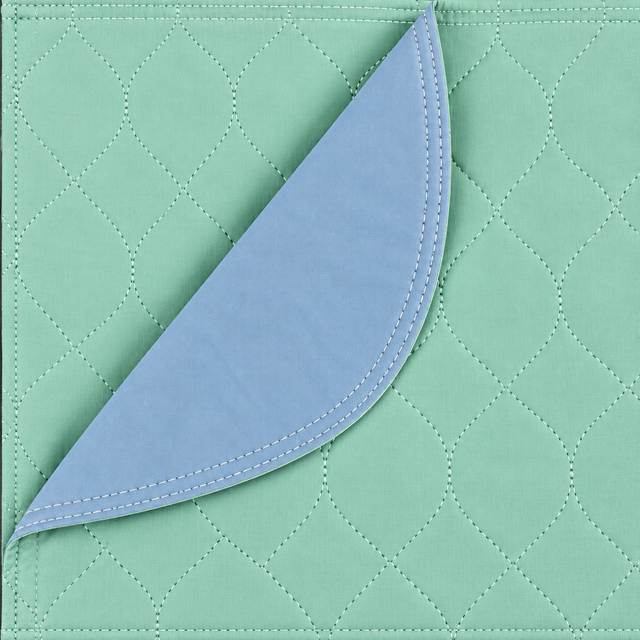 Pictured: The green Arid Touch Under Pad takes up the whole frame. It is partially folded over to show the blue vinyl lining that is on the bottom of the pad.