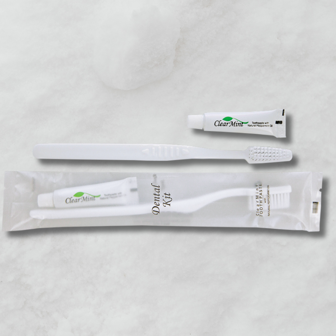 Pictured: A mini mint toothpaste tube, a white tooth brush, and a Dental kit sitting against a marble background. The dental kit comes in clear packaging, with the toothbrush and toothpaste as shown.