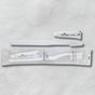 Pictured: A mini mint toothpaste tube, a white tooth brush, and a Dental kit sitting against a marble background. The dental kit comes in clear packaging, with the toothbrush and toothpaste as shown.
