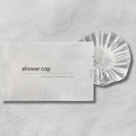 Clear shower cap on a gray background with packaging labeled 'shower cap'.