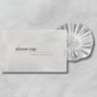 Clear shower cap on a gray background with packaging labeled 'shower cap'.