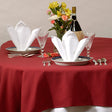 Pictured: Decorated banquet table with plates, glasses, silverware, a flower bouquet and a bottle of alcohol. On the plates are the white Dynasty Napkins which are folded very fancy in order to free stand. 