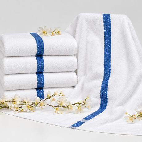 Pictured: On the left side is a neatly stacked pile of four Economy pool towels, decorated with little flowers. On the left, the pool towel is draped over an object to get a better idea of what the product looks like unfolded. The towels are white with a thick blue stripe down the middle.