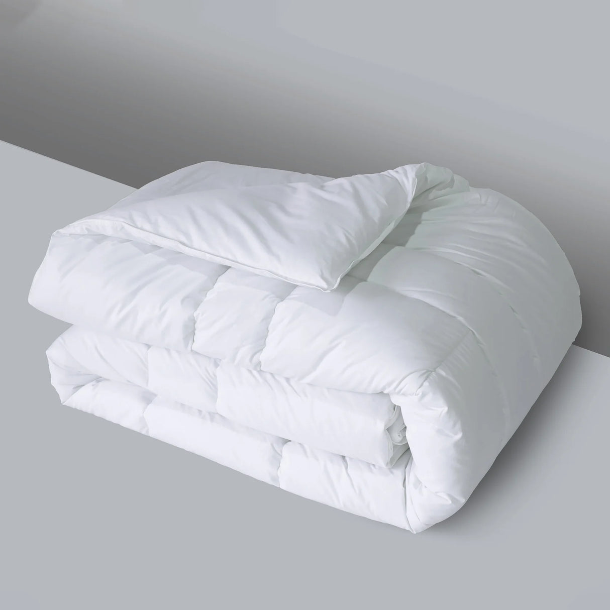 Folded white comforter on a gray surface