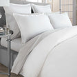 Pictured: Nicely made white bed on a gray bed frame with a mirrored side table to the left. The bedding features the Gryphon Supima Cotton T-360 sheets.