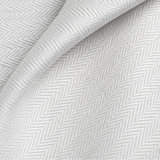 Pictured: Extreme closeup of the white fabric and herringbone pattern of the top sheet.
