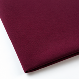 Pictured: Close-up of a neatly folded tablecloth against a white background. This tablecloth is in the shade Maroon.