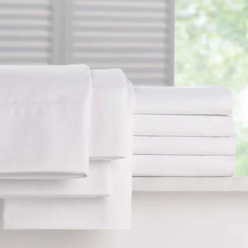 Pictured: Full Millennium t-200 Sheets, neatly folded and stacked atop a white counter in front of a window. The items you can get are the fitted sheet, the flat sheet and the pillowcases.