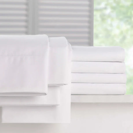 Pictured: Full Millennium t-200 Sheets, neatly folded and stacked atop a white counter in front of a window. The items you can get are the fitted sheet, the flat sheet and the pillowcases.