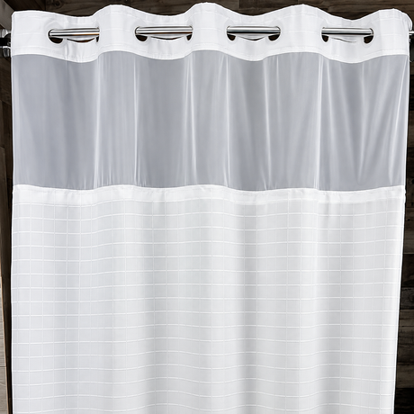 Pictured: White, hookless shower curtain hanging on a metal rod. The curtain has a box stitch pattern, with a sheer window about a quarter length at the top. The product is called the Millennium Shower Curtain. 