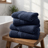 Pictured: Modern bathroom setting with 4 neatly folded stacked towels in the center. These navy towels are part of the Oxford Magic Bleachguard Collection
