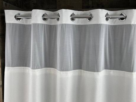 White shower curtain with silver rings on a dark background