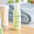 Pictured: Small standing green bottle with a clear cap in the forefront of a bathroom setting. The bottle is part of a spa line called Nourish, and it is the hydrating conditioner with green tea. The bottle holds 1 fluid oz. (30 mL)