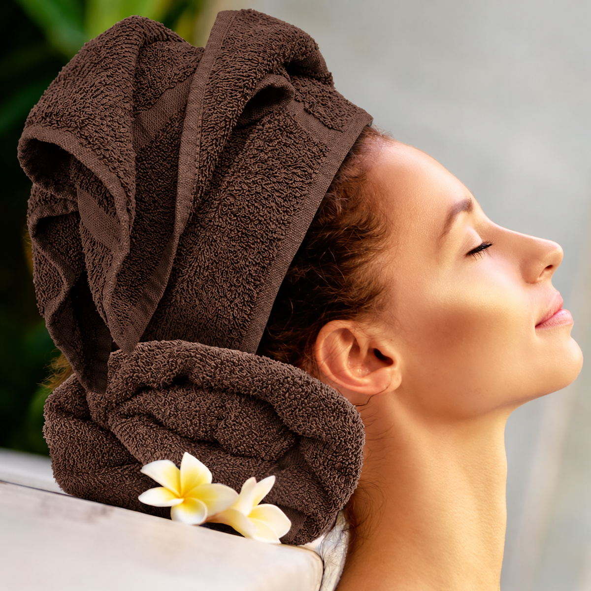 Pictured: Model leaning back on a neatly rolled towel, with their hair wrapped in the same colored towel. This is the Oxford Salon and Spa Towel in the shade Hazelnut.