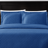 Pictured: Blue bedding on a dark wood bedframe. The bedding features the Radiance Diamond Quilted Sham, which has a diamond stitch creating a textured pattern.