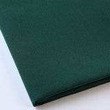 Pictured: Close up of the Premier Napkin neatly folded in the shade Forest Green against a white background.