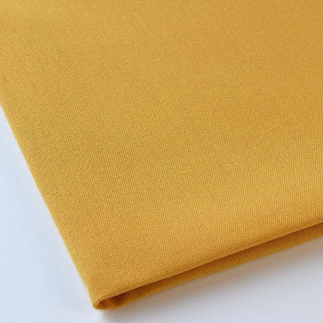 Pictured: Close up of the Premier Napkin neatly folded in the shade Gold against a white background.
