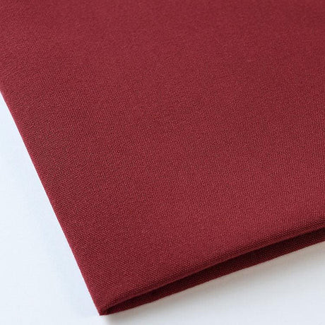 Pictured: Close up of the Premier Napkin neatly folded in the shade Maroon against a white background.