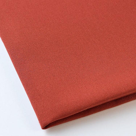 Pictured: Close up of the Premier Napkin neatly folded in the shade Rust against a white background.