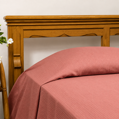 Pictured: Bedspread in the shade "Raspberry" on a wooden bed frame.